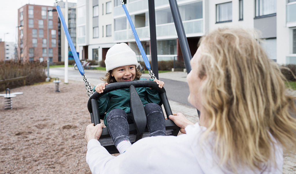 Asukas keinuttaa lastaan pihakeinussa.